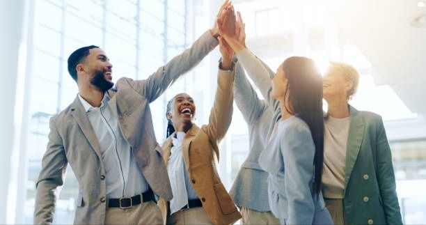 Fyra affärsklädda kollegor jublar och gör high five tillsammans