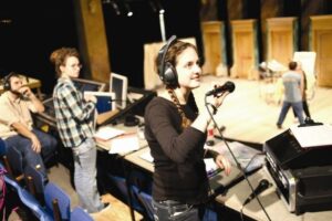 Person med headset och mikrofon arbetar vid scenkanten under repetition