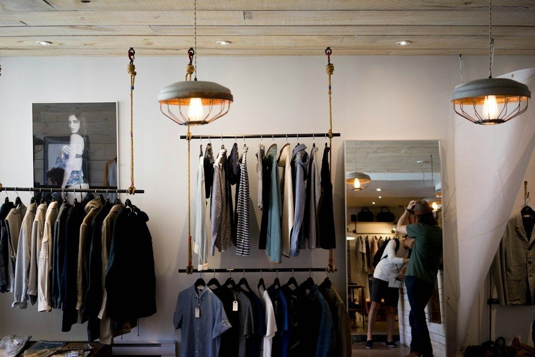 Kläder hänger i en modern butik med träinredning och repbelysning